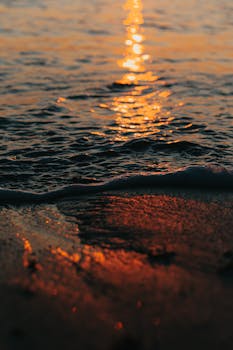 Close-up of ocean waves reflecting a golden sunset, creating a serene and warm atmosphere.