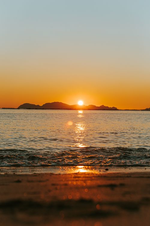 Free Serene beach scene with a stunning sunset over tranquil ocean waves. Stock Photo