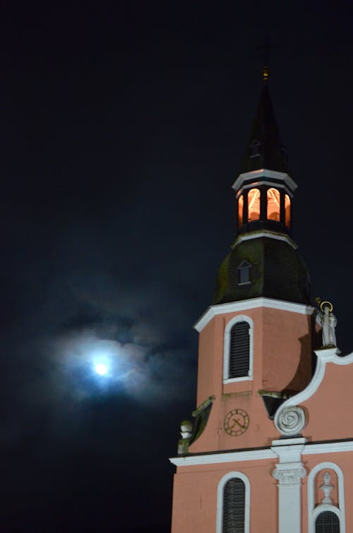 From below of exterior details and bell tower of Basilica of the Transfiguration of Our Lord located in Prum against dark cloudy night sky