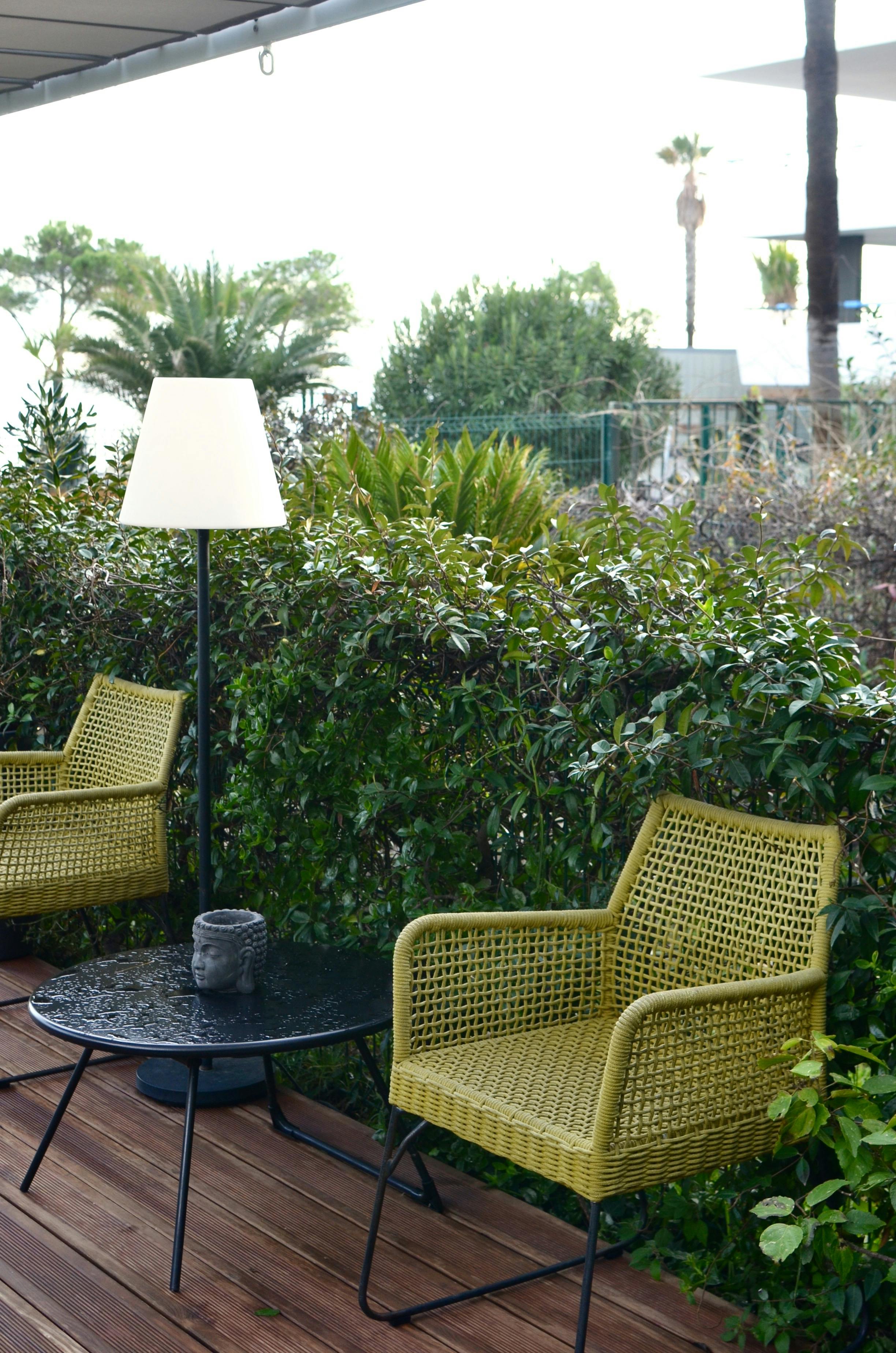 terrace with stylish wicker furniture in tropical resort on rainy day