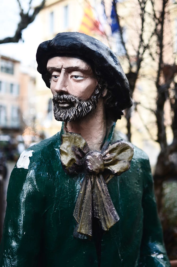 Old Sculpture Of Man In Historic Clothes Placed On City Square