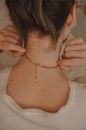 Woman putting on decorative golden necklace