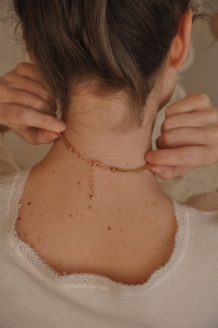 Woman Putting On Decorative Golden Necklace