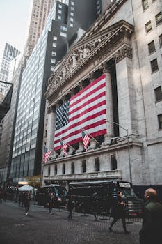 The New York Stock Exchange adorned with large American flags, bustling street life below.