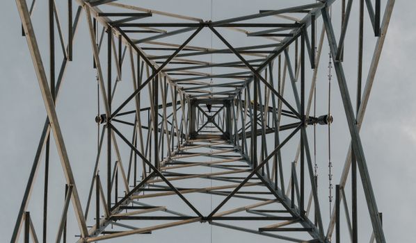 A downward symmetrical view through an industrial metal structure against a clear sky.