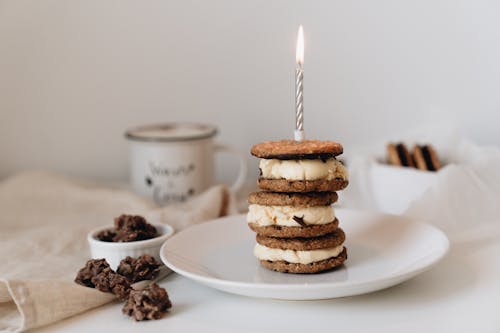 Cookie Sandwich on White Ceramic Plate with Silver Candle on Top