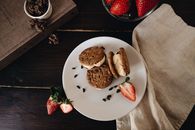 Tasty cookie sandwiches filled with cream and strawberries on a plate.