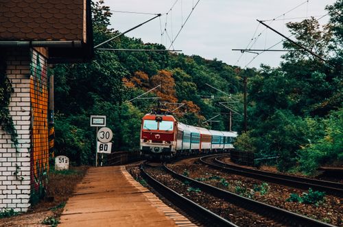 Free A train moves along railway tracks amidst a vibrant forest landscape near Bratislava, Slovakia. Stock Photo