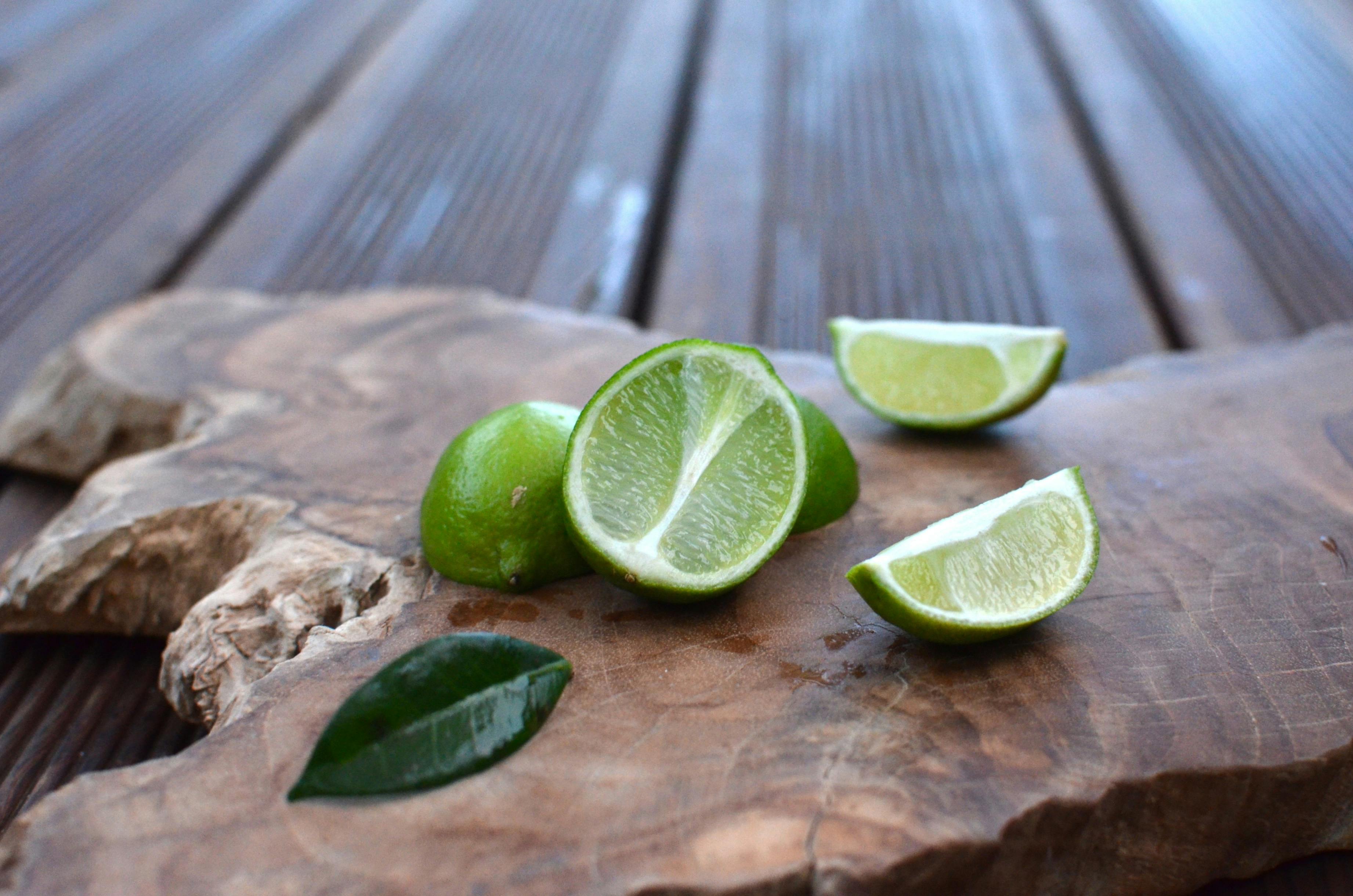 Close-up of fresh sliced limes on a rustic wooden board, ideal for food photography.