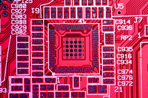 Top view of contemporary bright red printed board with electric circuits and various numbers with letters of modern electronic device