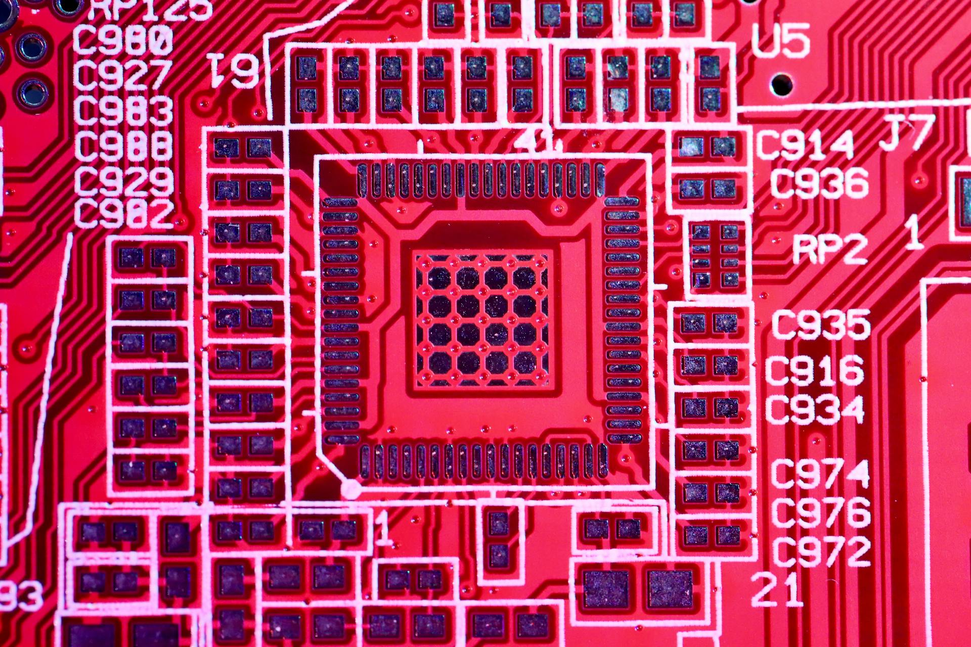 Top view of contemporary bright red printed board with electric circuits and various numbers with letters of modern electronic device