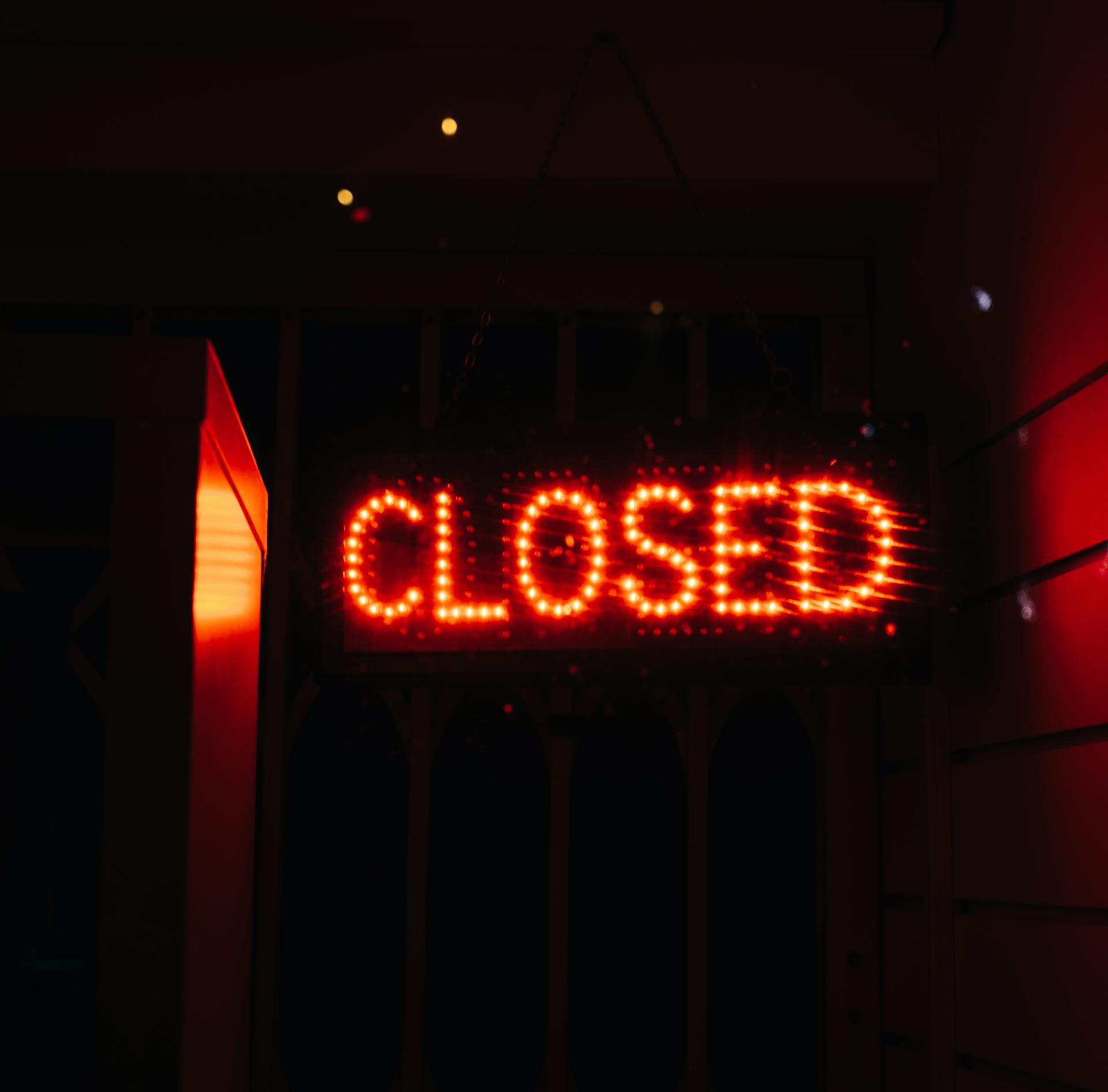 Bright red neon closed sign illuminating a dark space, conveying closure and night ambiance.