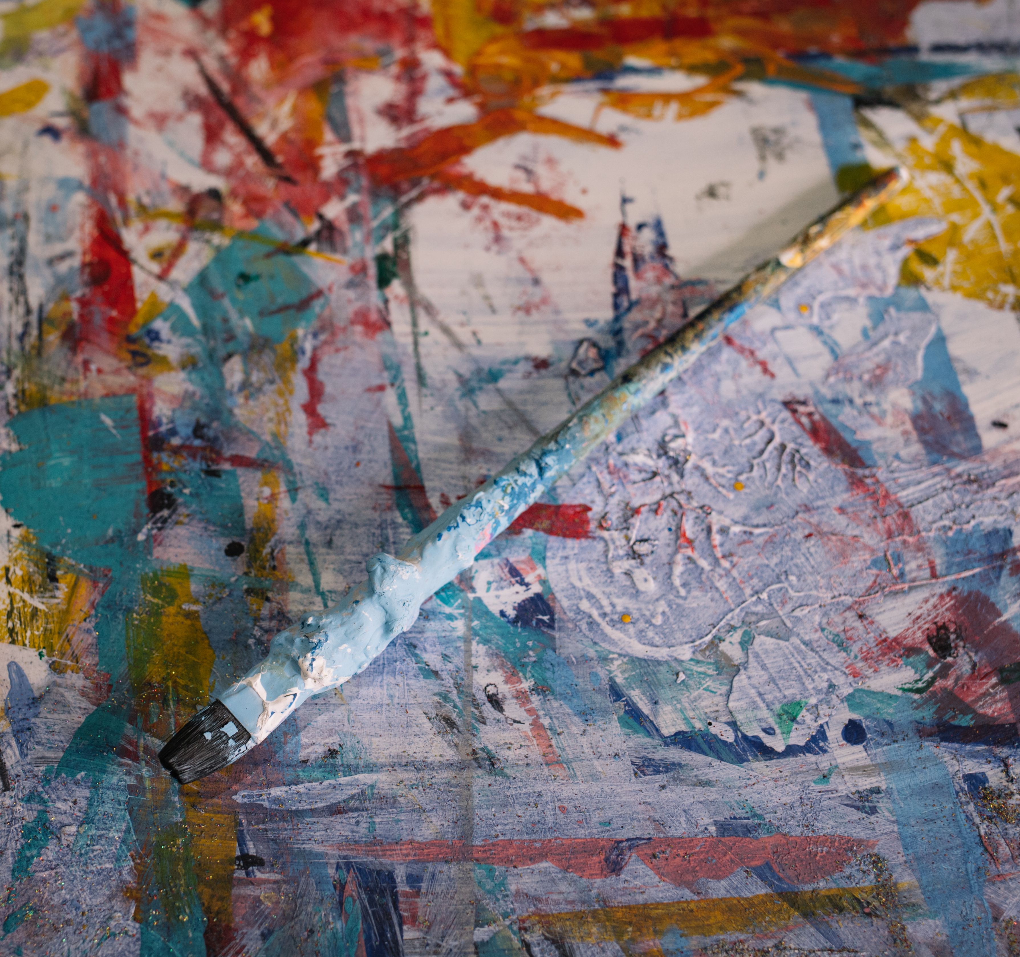 Artistic paintbrush lying on a colorful, abstract canvas, showcasing creativity.