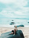 A Woman Sitting on a Rock Near the Seashore