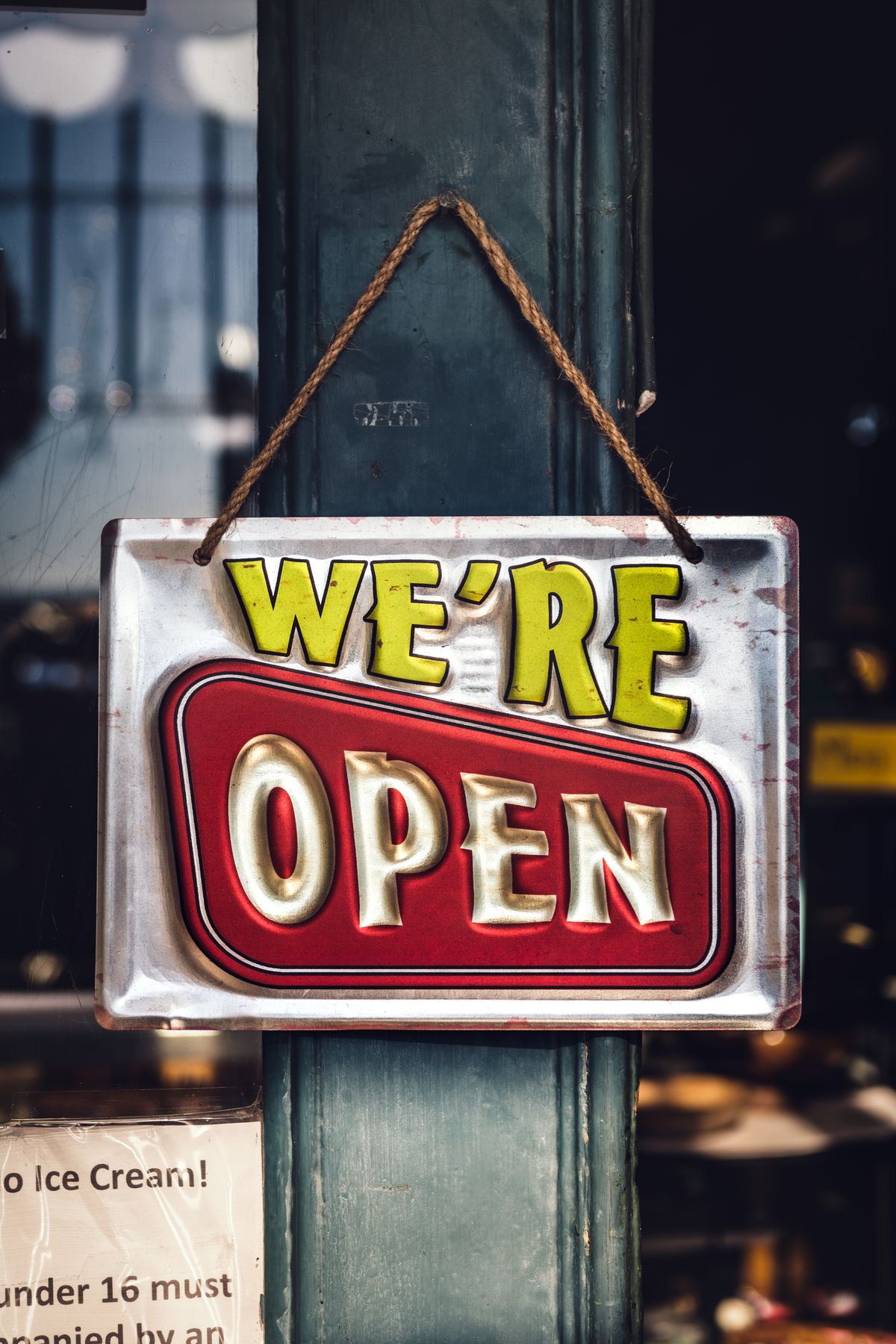 Semn clasic cu mesajul We're Open agățat pe ușa unui magazin