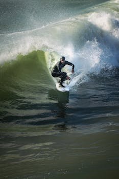 A surfer expertly rides a wave at Cayucos Beach, California under clear skies.