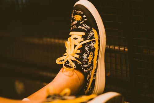 Free Artistic photo of black sneakers with yellow laces and graffiti design, showcasing urban street fashion. Stock Photo