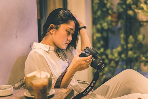 Woman Looking at Black DSLR Camera