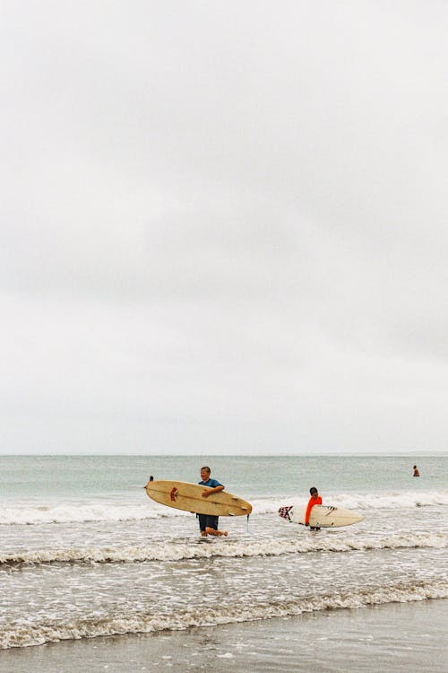 Two Men Holding Surfboards on Seashore