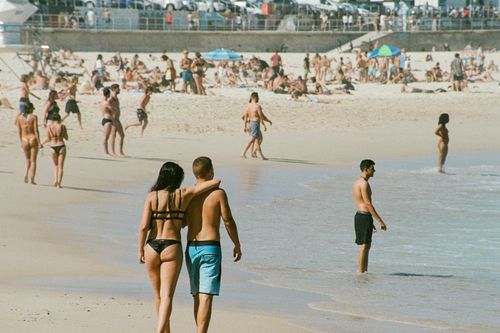 Free Crowded beach scene with tourists enjoying a sunny day and ocean waves. Stock Photo