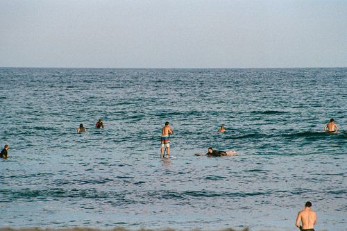 Free People enjoying swimming in the ocean on a sunny day which reflects a vibrant summer vibe. Stock Photo