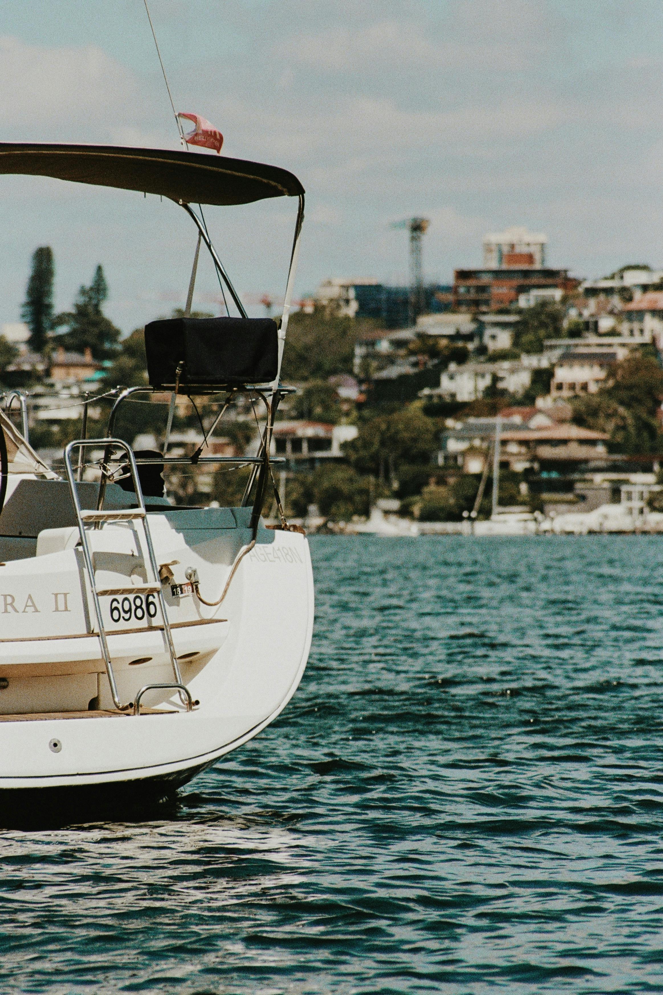 A serene scene of a yacht floating on calm waters, with a cityscape in the background.