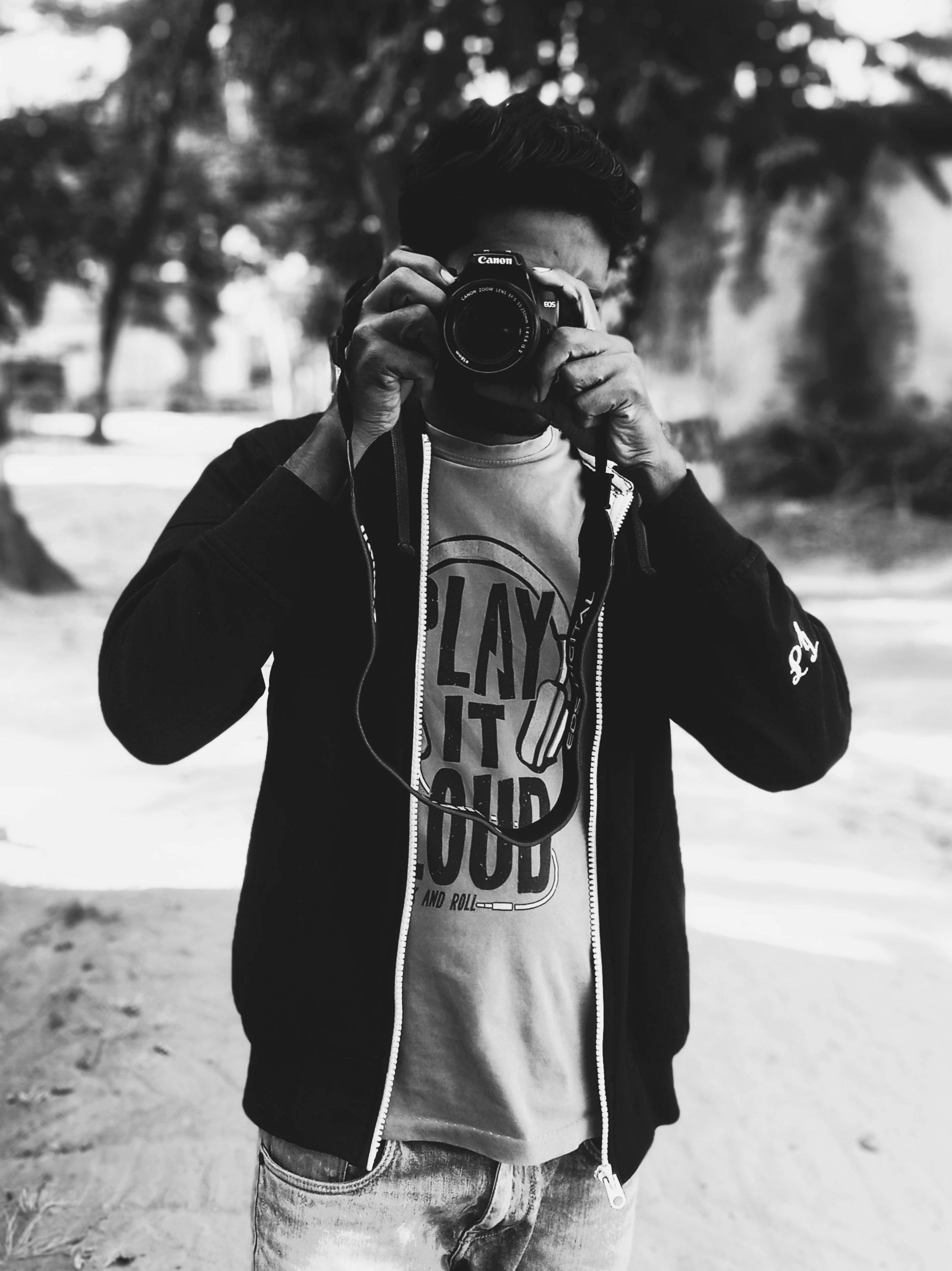 Black and white of anonymous male photographer in casual wear taking picture on photo camera while standing on street in city