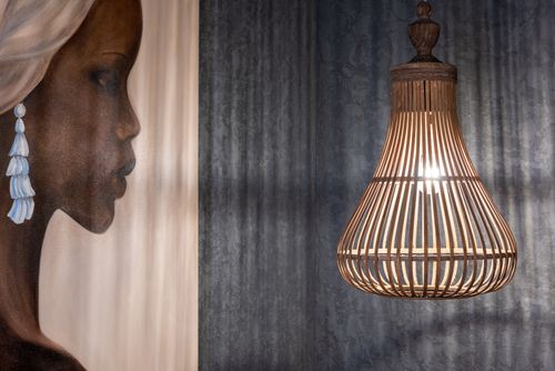Free Artwork of ethnic female in earring and headscarf on wall against glowing light bulb in decorative lamp Stock Photo