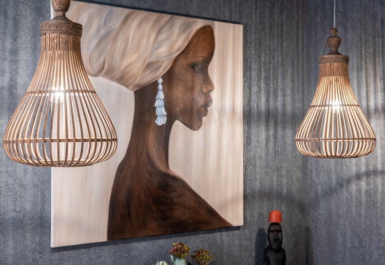 Painting Of African Woman On Wall Between Shiny Lamps