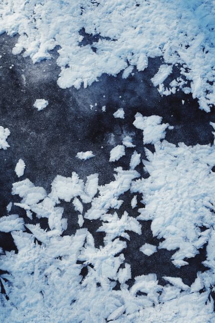 Detailed view of icy frost patterns on a frozen surface, highlighting winter's beauty.