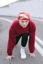 Woman in Red Long Sleeve Shirt and Black Pants Sitting on Road