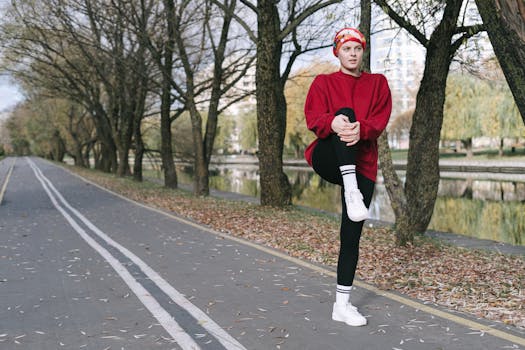 Caucasian woman in red sweatshirt stretches on a tree-lined path during autumn.