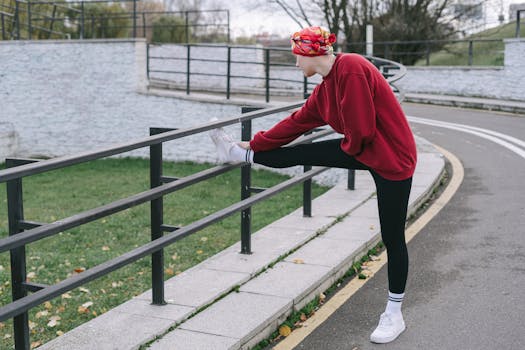Active woman stretching outdoors in a red sweater, promoting healthy lifestyle and fitness.