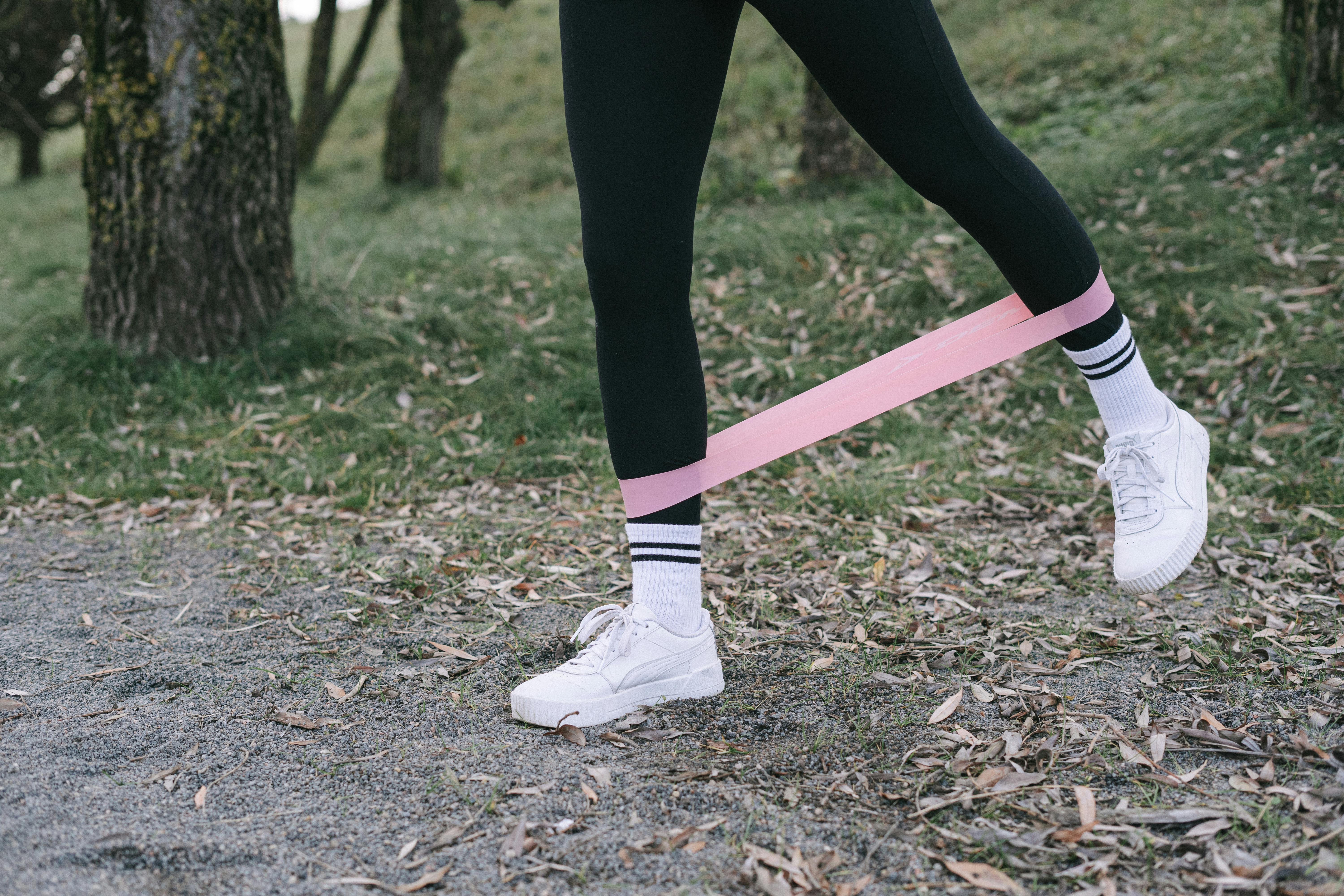 A Person in Black Leggings Working Out with a Pink Resistance Band