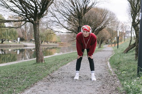 Woman in Red Sweater Standing on Dirt Path near the River