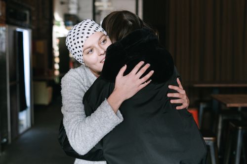 Free Two women hugging, showcasing support and compassion in cancer awareness indoors. Stock Photo