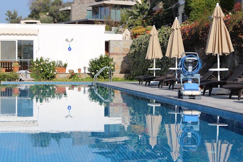 Lounge Chairs and Umbrellas Near Swimming Pool with Blue Water