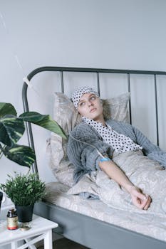A woman with cancer resting in a hospital bed, connected to an IV in a calm setting.