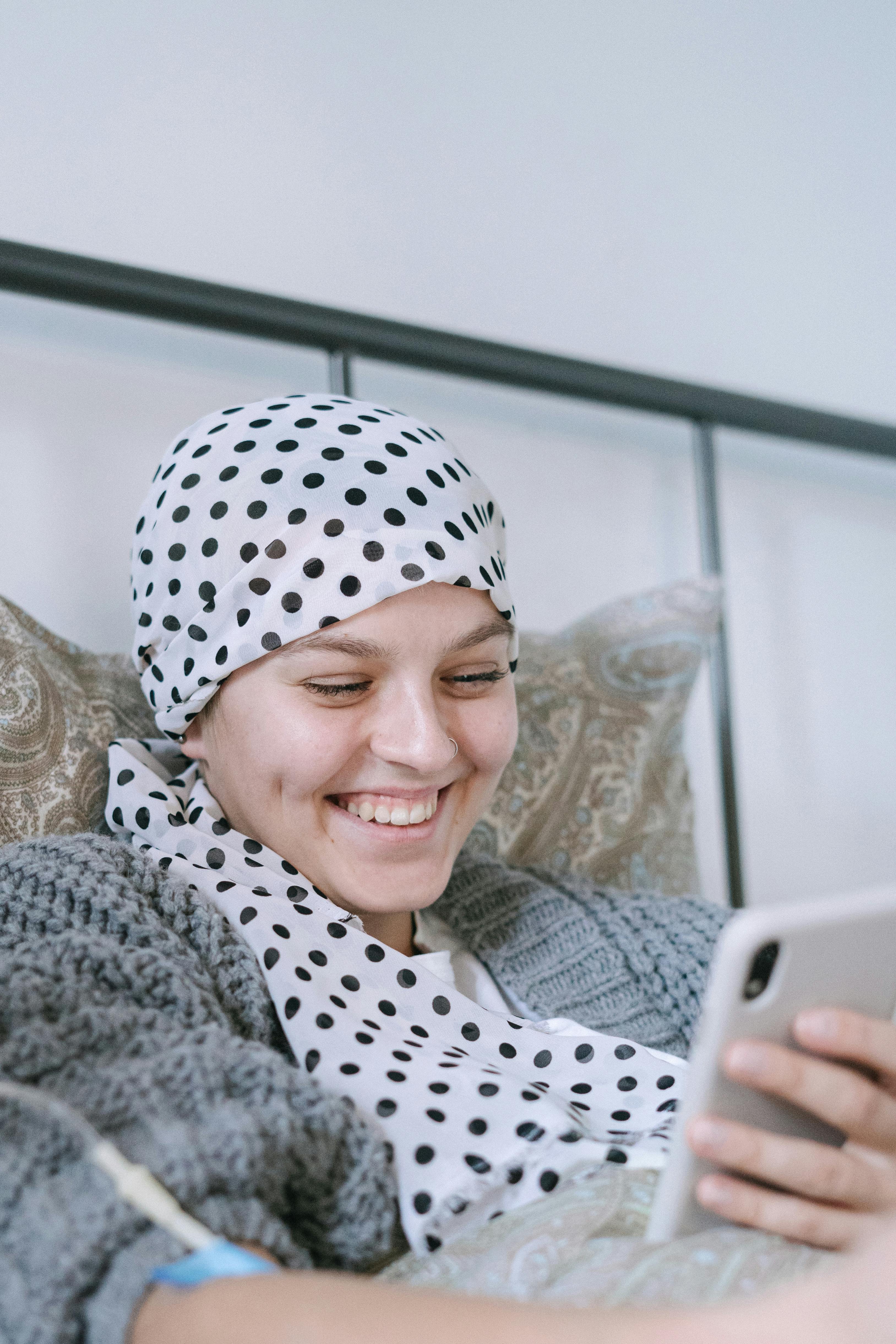 smiling woman in white and black polka dot hijab using silver ipad