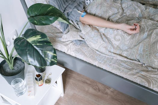 Close-up of a patient resting, surrounded by medicinal items and a bedside plant.