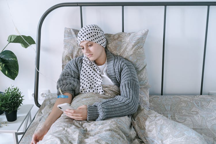 Woman In Gray Sweater Sitting On Bed