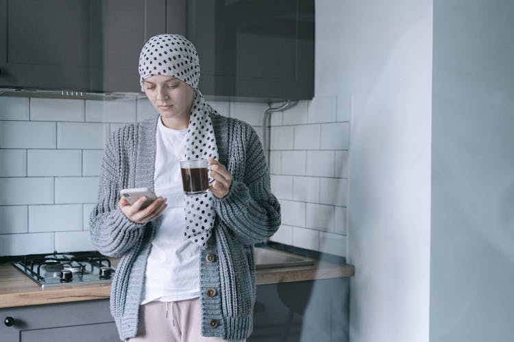 Woman Holding A Clear Cup With Coffee And Her Smartphone