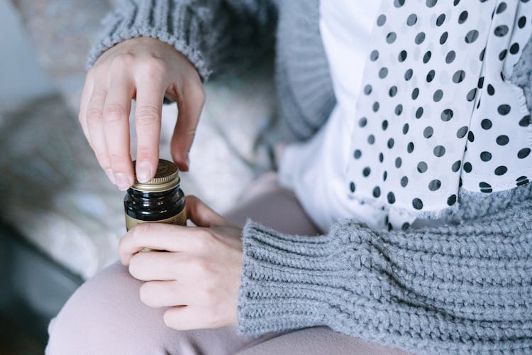 Person Holding Black Glass Bottle