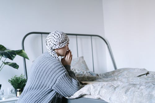 Woman in White and Black Hijab Sitting on Bed