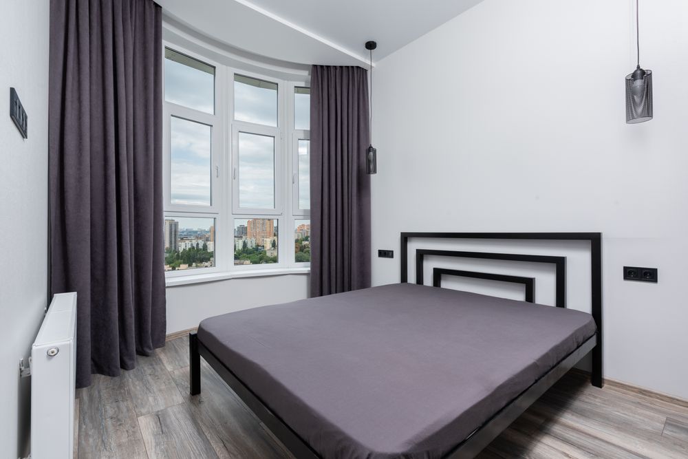 Contemporary bedroom with dark curtains near a large window
