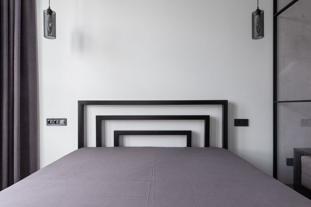 A calm grey treatment room with a bed and folded linen