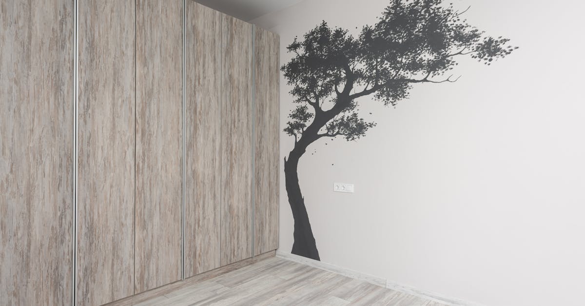 Minimalist room with a tree decal on a light wall, featuring wooden paneling and flooring.