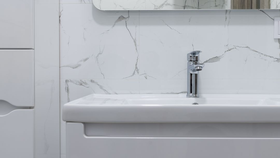 A bathroom washbasin and tap beneath a mirror