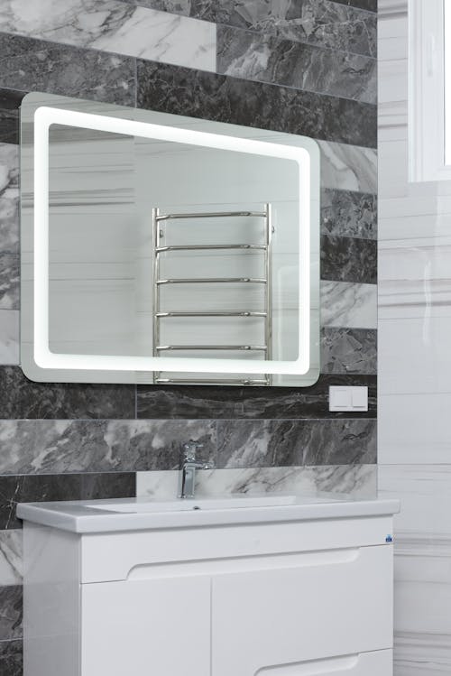 Free Contemporary bathroom with stainless steel tap and washstand under mirror reflecting metal rack in house Stock Photo