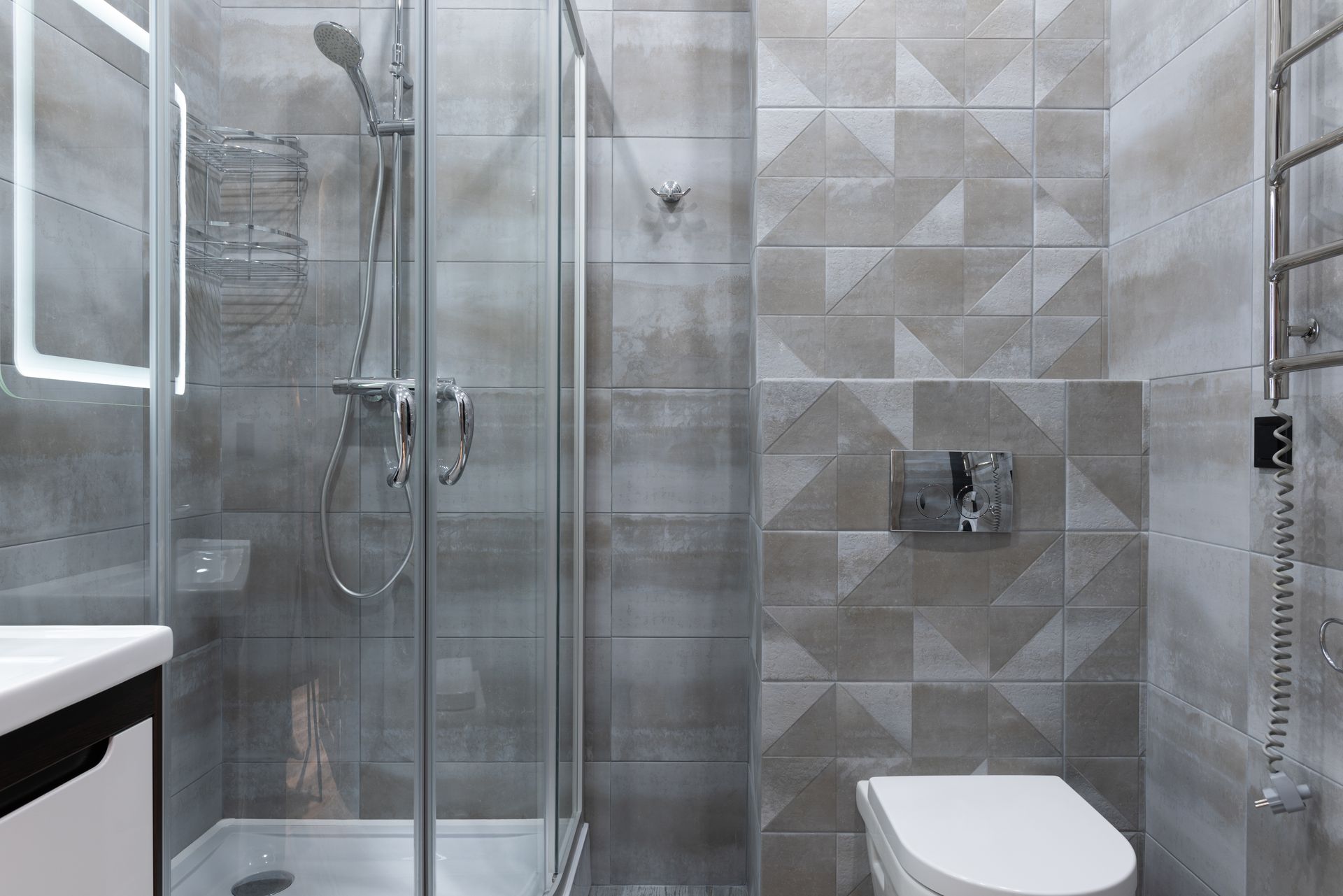 Contemporary bathroom featuring a sleek glass shower and geometric tiled walls.